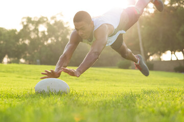 Rugby player athlete in action jumping in the air for the ball on the grass during summertime.