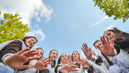 Obraz premium Happy Russian female graduates hug and wave their hands on graduation day.