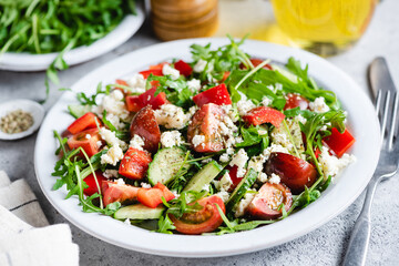 Vegetable salad with goat cheese, arugula salad leaf and cherry tomatoes on a flat plate