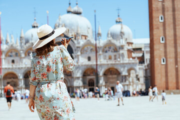 Seen from behind trendy woman in floral dress talking on phone