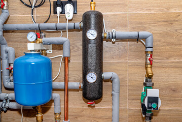 Obraz premium Expansion vessel to protect against overpressure and a hydraulic clutch in a modern natural gas boiler room, lined with ceramic tiles.