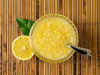 Top view of lemon freezer jam in a glass bowl over bamboo table mat. Fresh made no-cook jam of juicy lemons blended with sugar. Vitamin sweet sour puree of citrus without heating. - obrazy, fototapety, plakaty