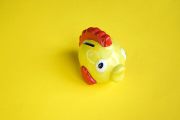 Yellow piggy bank in the form of a fish on a yellow background.