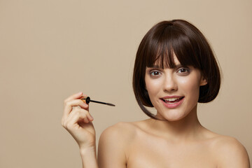 Obraz premium young woman paints eyelashes bare shoulders isolated background