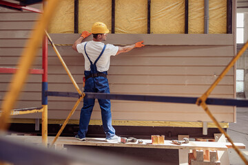 Male worker building cabin at construction site - obrazy, fototapety, plakaty
