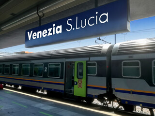 Venice Santa Lucia railway station sign with a stationary train in the background. Venice city,...