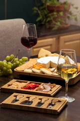 Formal fancy and elegant wooden cheese board with fruit, cheese, meat and wine sitting on a kitchen counter inside