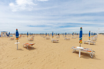 Daylight landscape of an empty beach, sun umbrellas and benches are visible but there are no people.