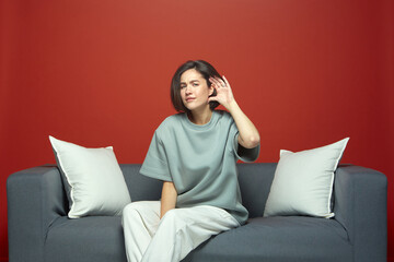 Attentive young girl hold hand near ear trying to listen quiet conversation, having hearing problems, sitting on sofa