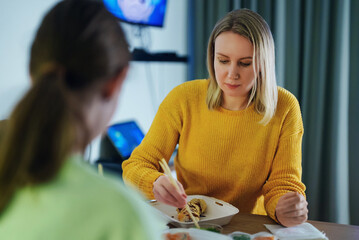 Fototapeta premium Mom and daughter eat sushi at home.