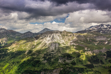 Austrian Alps. Mount Grossglockner. Highlands in summer. High mountains in the shadow of clouds and the rays of the sun. Mountain landscape. Juicy greens. Cloudy sky.