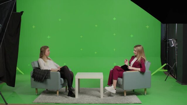 Young female patient and woman psychologist at psychotherapy session over green screen background. Youth talk show interview with a famous guest