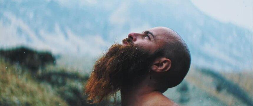 Man looks up to the sky as rain pours down