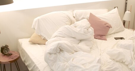 Bedroom interior in the morning. A bed with blankets and pillows without anyone. No people. The phone is on the sheet.