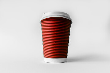 Disposable red paper cup for coffee on a gray background.