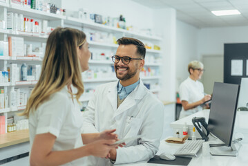 Obraz premium Male pharmacist working with young female colleague in a pharmacy