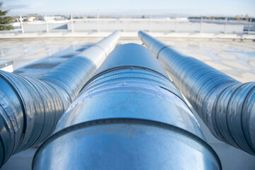 Air extractor and large galvanized steel pipes on the roof of a warehouse