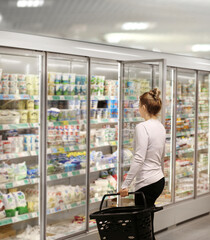 Fototapeta na wymiar Woman choosing frozen food from a supermarket freezer.