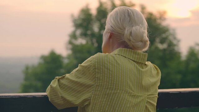 Lonely senior lady standing near fence, looking into distance, missing children
