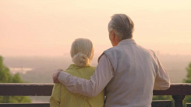 Happy senior couple enjoying sunset view together, loving husband hugging wife