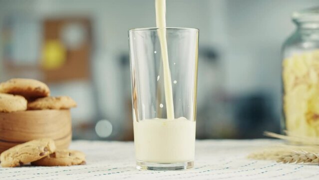Pouring yogurt into glass cup close-up. Glass with kefir or milk, dairy products concept. Drinking fresh lactose-free milk in morning.