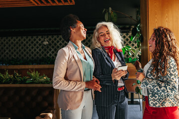 Diverse happy women using phone at cafe