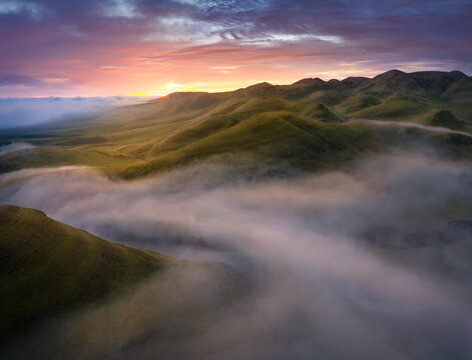 Colorful sunrise above patchy fog in rolling hills, central California, USA