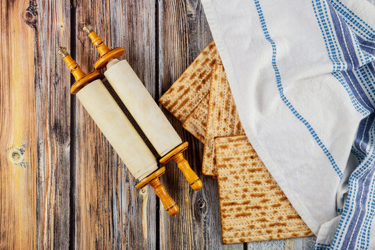 Matzah, tallit and torah on wooden background.