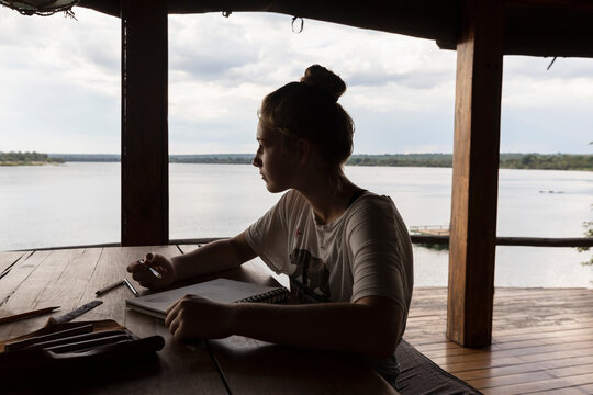 Africa, Zambia, Livingstone, Girl (16-17) relaxing in lodge by Zambezi River