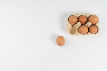 chicken brown eggs lie in a box and one next to it, on a white background.There is space for text