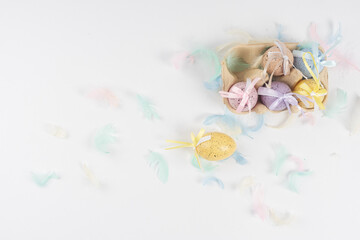 chicken, painted eggs for Easter, lie in a box and next to each other, decorated with colored feathers on a white background.There is space for text