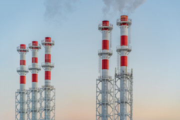 Smoking Chimneys. Factory chimneys with thick smoke against the background of sunset sky