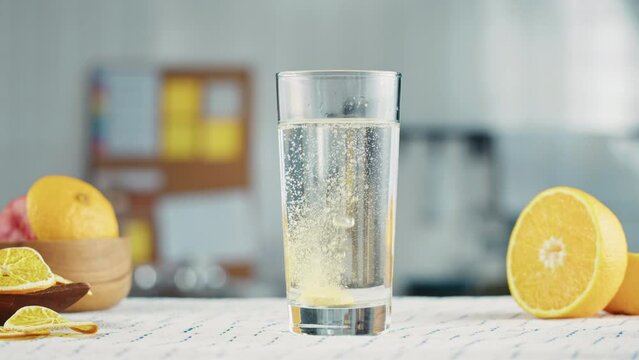 Effervescent tablet vitamin C nutritional supplements in glass with yellow carbonated water, sport medication, healthy morning. Aspirin antipyretic drugs
