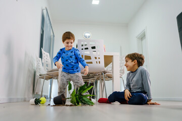 two caucasian boys making mess in the house brothers playing and mischief with bad behavior flower...
