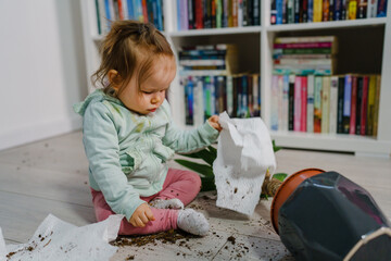 one caucasian baby girl making mess playing and mischief with bad behavior ripping paper towel and...