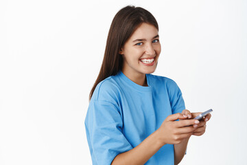 Portrait of smiling girl using mobile phone, looking happy at camera. Concept of cellular technology and smartphone