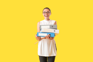 Beautiful young woman with folders on color background
