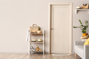 Stand with female accessories, sofa and houseplant in hallway