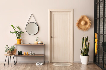 Interior of hallway with stand for shoes, mirror and houseplants near light wall - obrazy, fototapety, plakaty