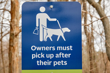Owners must pick after their pets sign in a wild outdoor wooden park