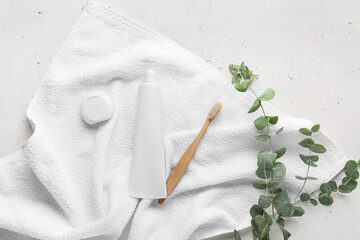 Tube with tooth paste, brush, dental floss and towel on light background