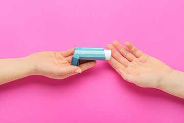 Female hands with inhaler on color background