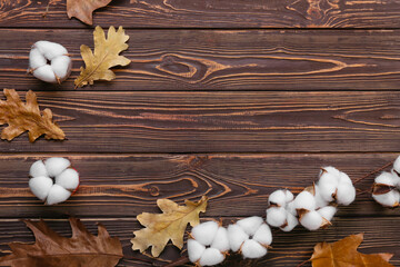 Cotton flowers and autumn leaves on wooden background