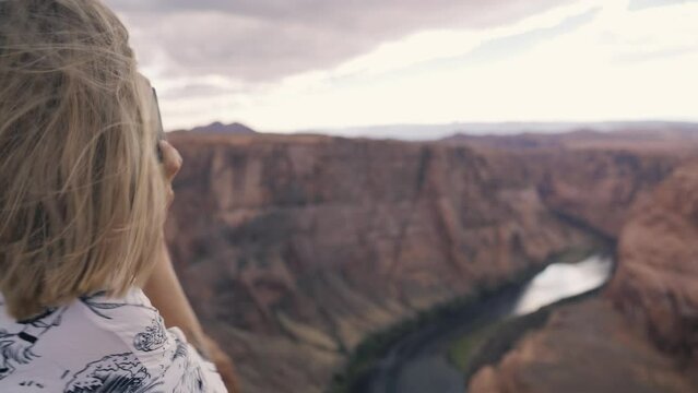 Young woman taking photograph of panoramic view of Horseshoe Bend at Utah, USA. Travel, adventure, destination and mindfulness concept.