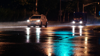 Rainy night in city, cars driving on wet road, rain was illuminated by the headlights of cars,...