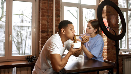 Couple eat noodles for video on smartphone