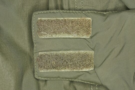 two plastic velcro fasteners on the green fabric of the collar on the jacket
