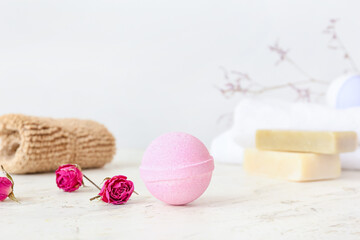 Bath bomb and rose flowers on light background