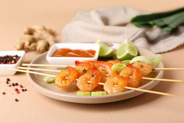 Plate with grilled shrimp skewers and sauce on beige background
