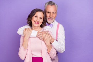 Portrait of two idyllic cheerful elderly partners hug trust care isolated on violet color background